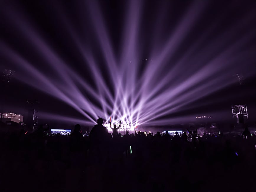 A lively night concert with beams of colorful lights and an energetic crowd