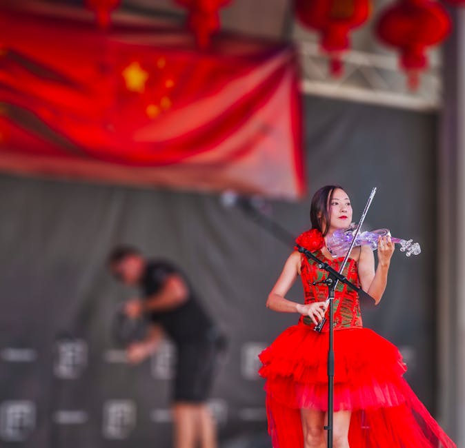 A talented violinist performs on stage in a vibrant red dress during a cultural festival